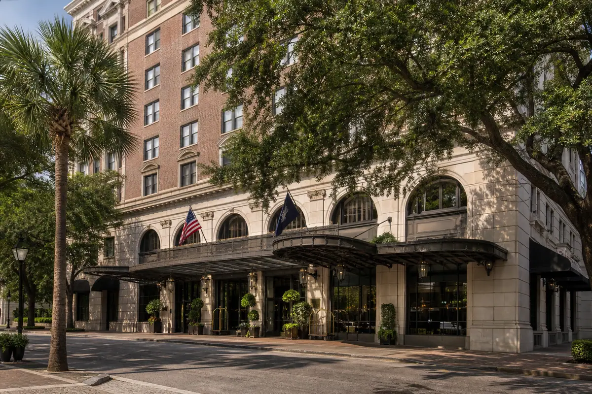 Photoreal exterior of The Charleston Place with cream facade, awnings, and palms