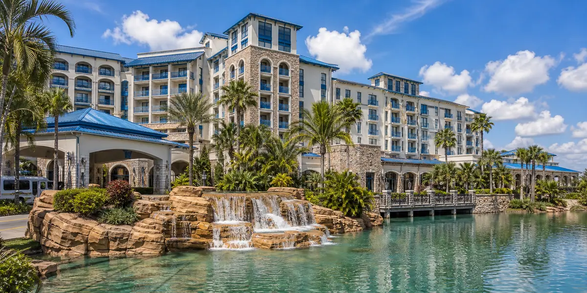 Photoreal tropical resort exterior with waterfalls and palms representing Loews Sapphire Falls Resort