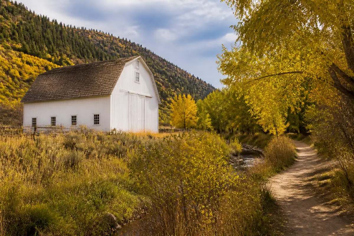 Photorealistic travel-editorial view of McPolin Barn and McLeod Creek Trail in Park City, Utah
